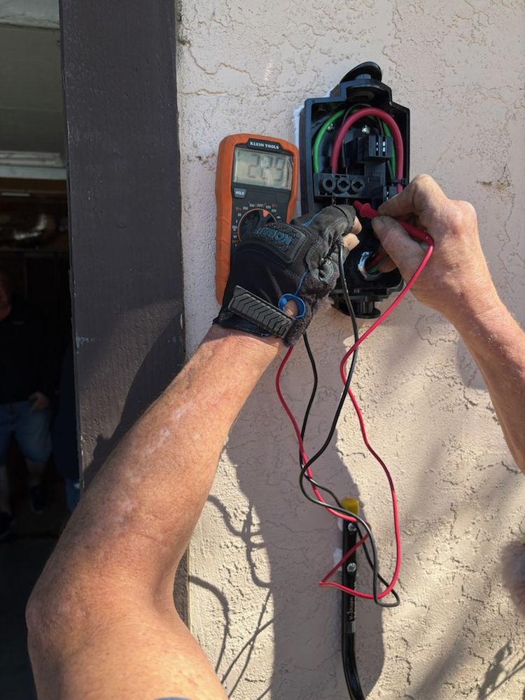 Electrician testing the circuit at an EV charger with a multimeter