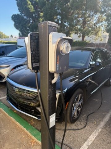 Dual-port EV charging post with a car plugged in